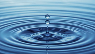 A close-up shot captures the graceful descent of water drops, creating ripples and a mesmerizing