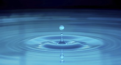 A captivating macro shot of a water droplet creating ripples and reflections, set against a dark