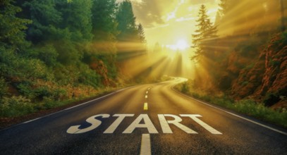 An open road with the word 'start' painted on it, illuminated by sunlight and surrounded by green