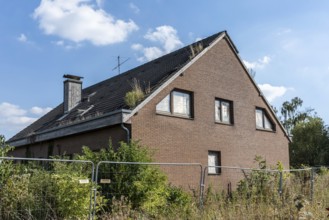 Overgrown house behind fence with plants on the roof, Manheim, North Rhine-Westphalia, Germany