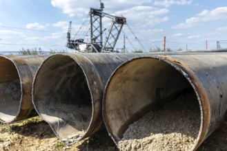 Large excavator in open-cast mine with pipes in the foreground, Manheim, North Rhine-Westphalia,