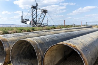 Large excavator in open-cast mine with pipes in the foreground, Manheim, North Rhine-Westphalia,