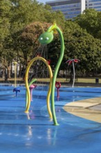 Large green dragon water play equipment with tower block in the background, Cologne, North