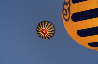 Two yellow-blue hot air balloons floating in front of a clear blue sky, Göreme National Park,