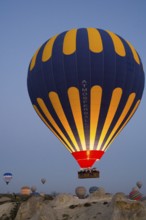 Balloons of different colours rise calmly into the morning atmosphere over the vast terrain, Göreme
