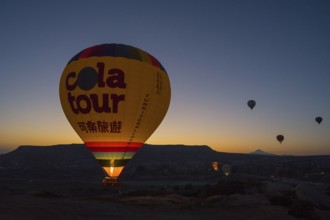A colourful hot air balloon rises into the quiet sky at sunrise, Göreme National Park, Göreme