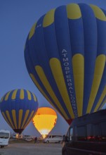 Hot air balloons stand ready at dusk, illuminated against a dark sky, camper, motorhome, Göreme