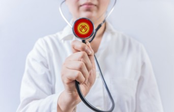 Female doctor holding stethoscope with Kyrgyzstan flag. National health system of Kyrgyzstan