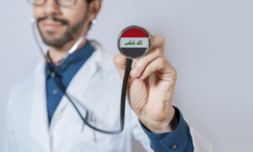 Doctor holding stethoscope with Iraq flag. Iraq health and care concept, Iraq flag on stethoscope