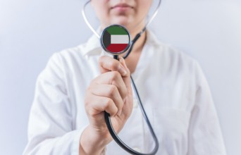 Female doctor holding stethoscope with Kuwait flag. National health system of Kuwait