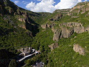 Gorge with lush greenery and rocks under a blue sky with clouds, aerial view, Geghard Monastery,