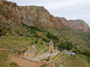 Church landscape in front of dramatic rock formations, surrounded by green nature, in a secluded
