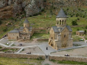 Old church in rural area with stone buildings and green landscape surrounded by mountains, aerial
