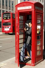 Red telephone box with smiling person and double-decker bus, London, London region, England, United