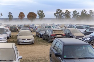Dusty parking space scenery on a field including lots of dust covered cars at evening time in