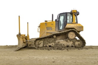 Yellow bulldozer at a loamy construction site, partly isolated in white back