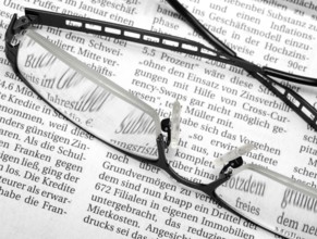 Newspaper detail with pair of glasses