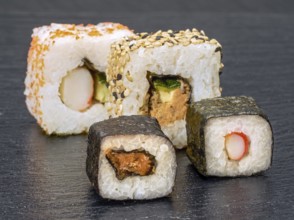 Various sushi dishes on dark grey stone surface