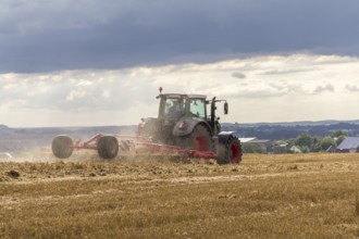 Tractor on a stubble field in stormy ambiance