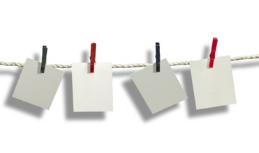 Clothesline with some light grey labels fixed with clothes pins in front of white back with shadow