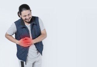 Man suffering with liver pain on isolated background. Young man with abdominal pain
