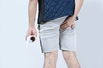 Man with diarrhea holding toilet paper an his anus