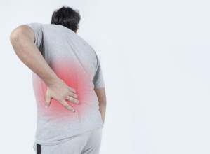Young man with back pain highlighted in red. Male with lower back pain on isolated background