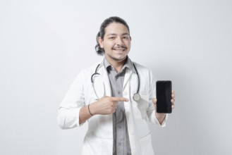 Smiling young doctor pointing at the phone