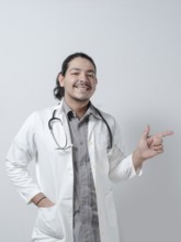 Smiling young doctor pointing to the right on isolated