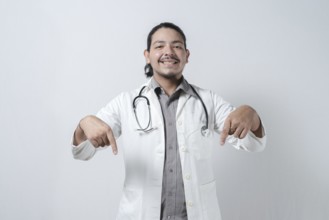 Smiling doctor pointing down isolated. Young latin doctor pointing down isolated