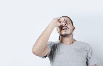 Young man with nosebleed on isolated background. Person with sinusitis or epistaxis. Concept of a