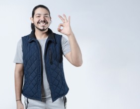 Smiling man making approval gesture on white background