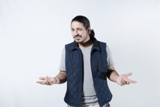 Confused young man with arms at his sides. Young male gesturing confusion on isolated background