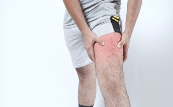 Closeup of sore knee on isolated background. Male holding his knee in pain on isolated