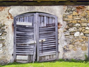 Large, weathered wooden gate in stone wall, emphasises rustic character Styria Austria