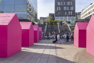 Twelve houses in bright magenta stand on Stuttgart's Schlossplatz in front of the art museum. The