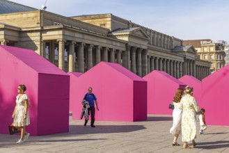 Twelve houses in bright magenta stand on Stuttgart's Schlossplatz in front of the art museum. The