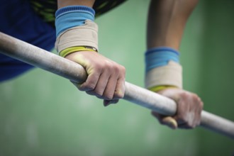 Close up of a gymnastics athlete gripping a sports bar with white chalk on their hands, AI