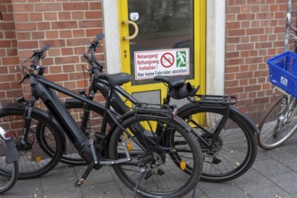 Bicycle traffic in Münster, bicycles parked on the pavement, in front of an emergency exit, which