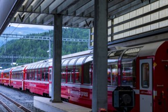 Railroad Station and Red Bernina Express Train with Mountain View in a Sunny Summer Day in