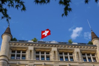Beautiful Swiss Flag on a Old Building with Towers Against Blue Sky in a Sunny Summer Day in
