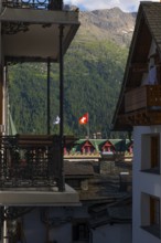 Beautiful City with Swiss and Grisons Flag and House and Mountain in the Swiss Alps with Blue Sky