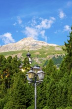 Church Tower and Street Lamp in the Forest and Mountain in the Swiss Alps in a Sunny Summer Day in