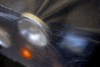 Car Lamps on the Front of a an Old Classic Car Covered with Plastic Protection in Switzerland