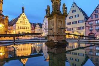 The market square with the Ratstrinkstube is reflected in the Georgsbrunnen fountain at dusk,