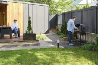 A couple spends the day outdoors at their contemporary home. The wife is seated on a patio, while