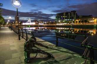 Sculpture of a harbour worker, building on the River Liffey, night shot, Dublin, Ireland