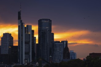 The sun breaks through the clouds behind the Frankfurt banking skyline shortly in front of setting,