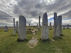 A mystical stone circle under a cloudy sky surrounded by green landscape, Callanish, Isle of Lewis
