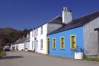 Colourful row of houses along a rural road under a bright blue sky, Knoydart, Highlands, Scotland,